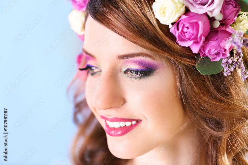 Beautiful young woman wearing floral headband on a blue background Beautiful young woman wearing floral headband on a blue background