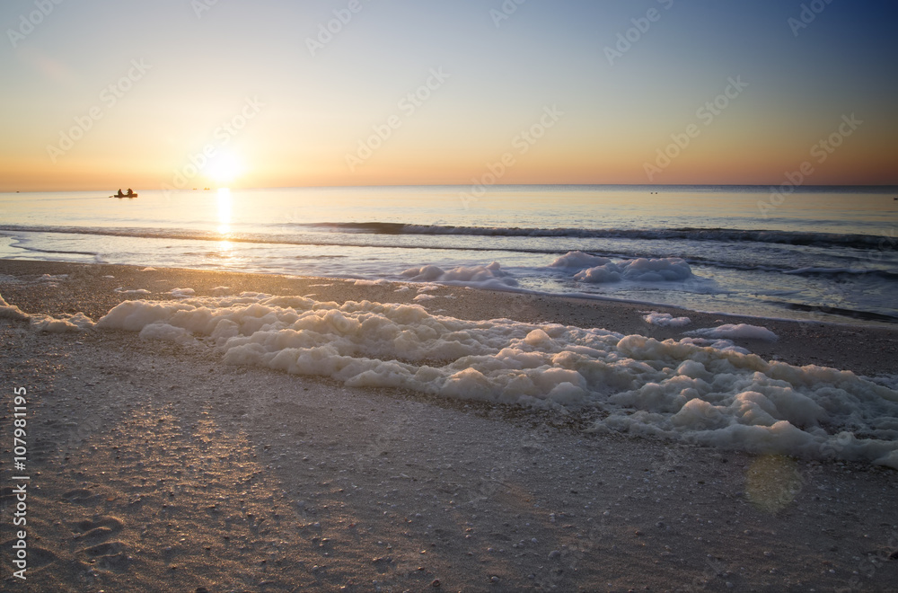Dawn on the sea, sea foam on the shore, the fishermen on the boa