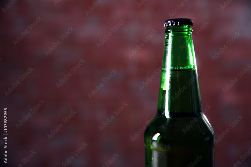 Green glass bottle of beer on blurred background, close up Green glass bottle of beer on blurred background, close up