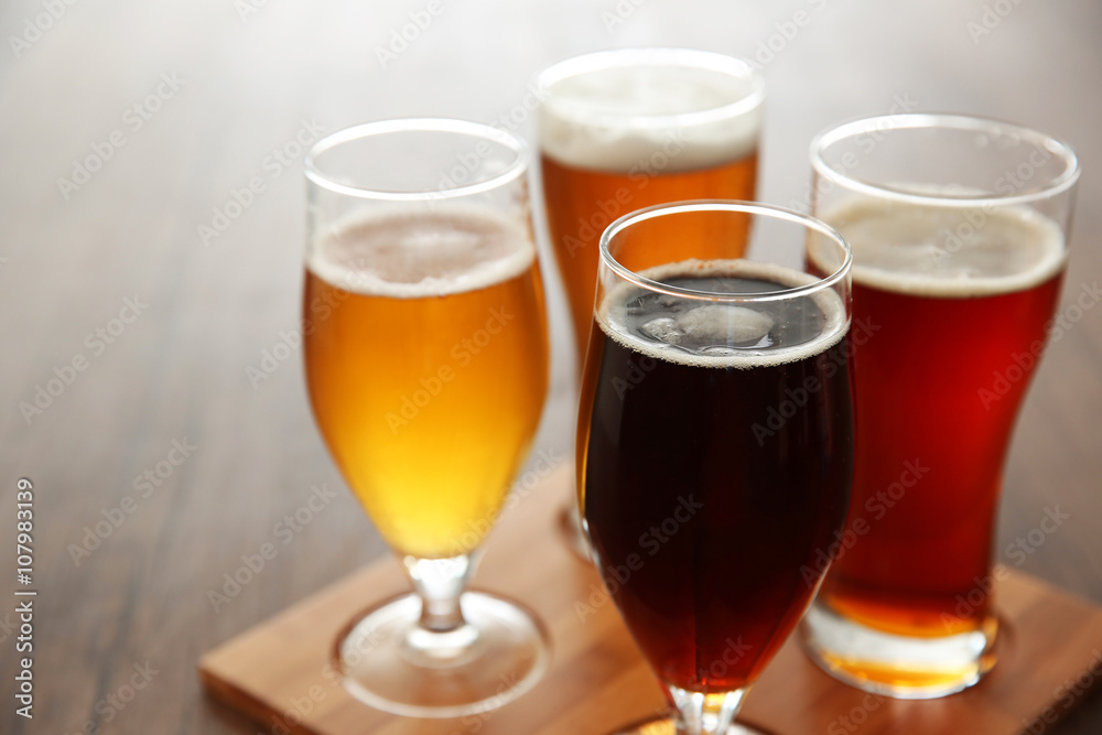 Glasses with different sorts of craft beer on wooden tray Glasses with different sorts of craft beer on wooden tray