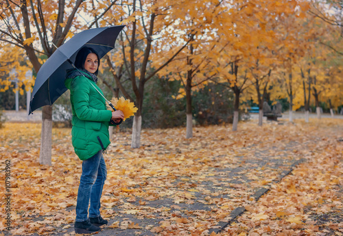 Single woman standing on sidewalk with leaves