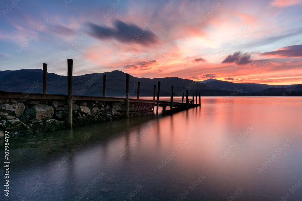 Beautiful colourful sunset with a wooden jetty in the Lake District, UK.