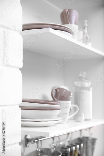 Dishware on a kitchen shelves © Africa Studio