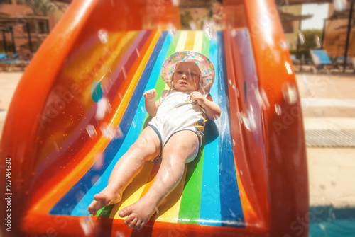 Little baby on a rainbow slide in aquapark