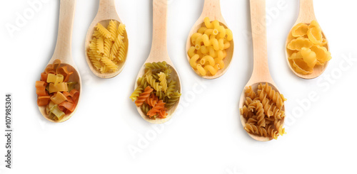 Samples of dry pasta in a wooden spoons, isolated on white