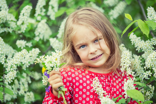 Portrait of happy little girl in spring flowers