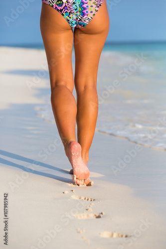 Woman legs walking on the beach sand 