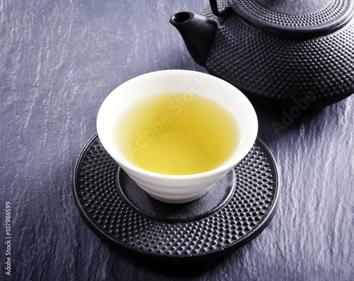 Pouring green tea into white pialat on slate plate background