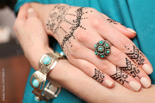 Female hands with henna tattoo on blue fabric background