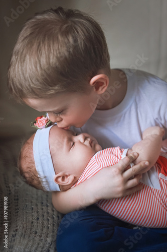 6 year old Boy kissing his 3 month old baby sister 