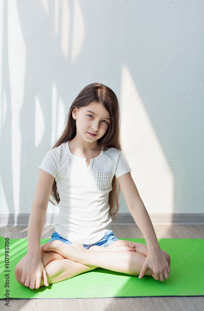 Foto de little girl doing gymnastics on a green yoga mat. doing