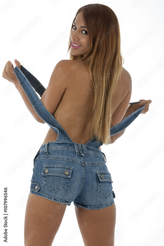 Sexy woman in only denim overalls, looking at camera and smiling. implyed  nude. Shot on a white background Stock Photo | Adobe Stock