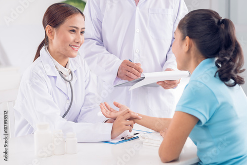 Smiling Vietnamese nusrse checking heart rate of patient