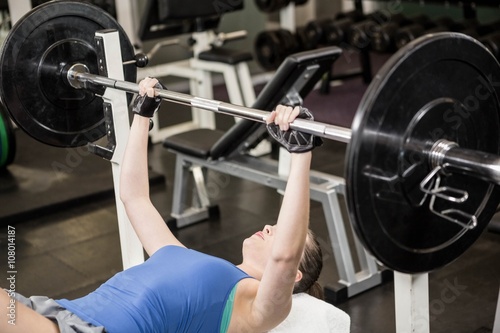 Fit woman lifting the barbell on bench