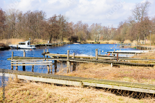 Jetties along Lyckeby river in Sweden in spring. Most of them are emtpy. Nature is bare. Weather is sunny and warm.