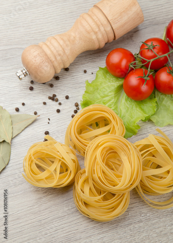 Pasta, tomatoes and pepper on a wooden background