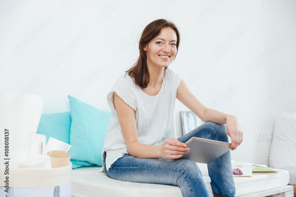 Cheerful charming woman artist with tablet sitting and smiling