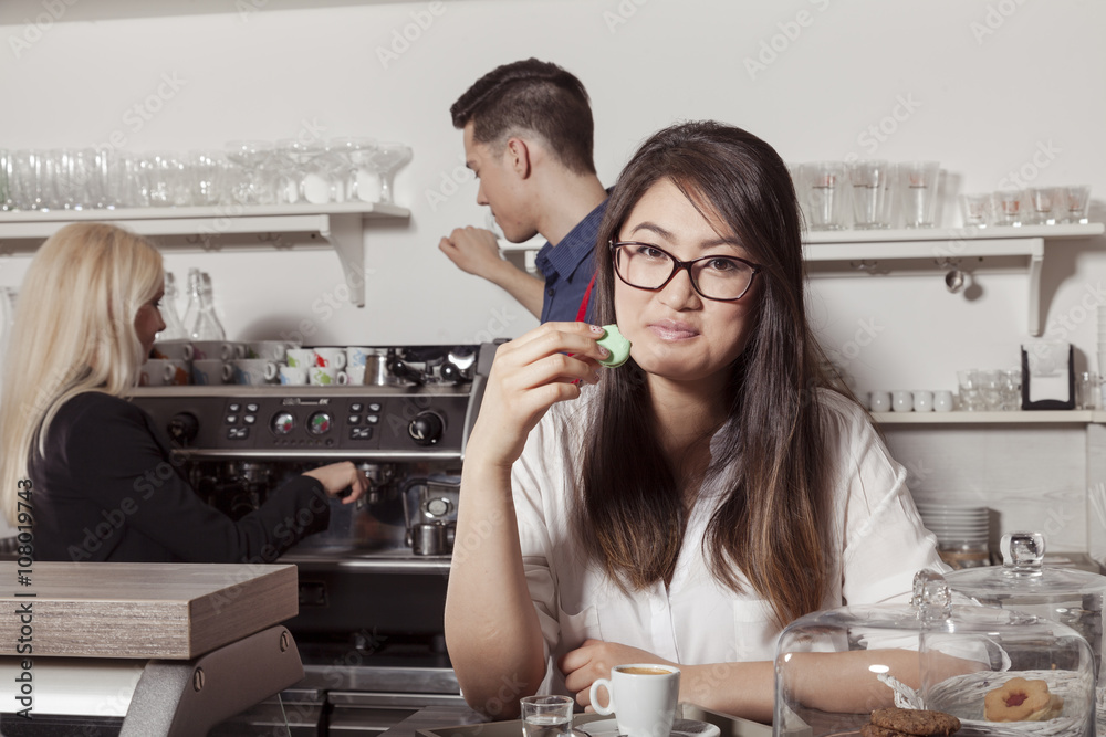 Asiatin ißt eine französische Makrone in Cafeteria Umgebung Asiatin ißt eine französische Makrone in Cafeteria Umgebung