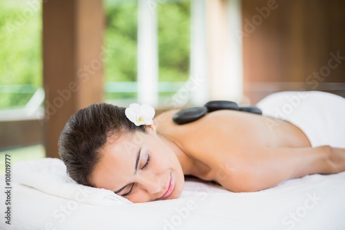 Young woman lying with spa stones at her back