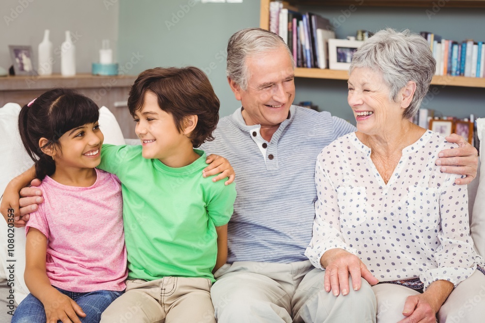 Happy grandchildren with grandparents on sofa at home Happy grandchildren with grandparents on sofa at home