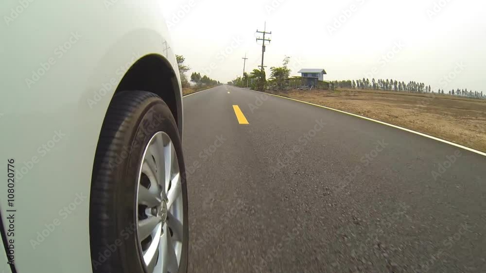 Driving a car on a country road, wheel spinning.
