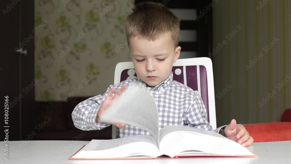 Boy turning the pages of big book as if reading then smiling at the camera and sneezing Boy turning the pages of big book as if reading then smiling at the camera and sneezing