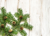 Christmas background, white shabby chic decoration with green fir tree branch and pine cones on wooden board