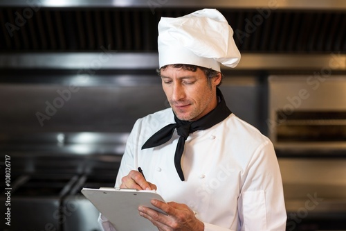 Chef writing on clipboard in kitchen photo