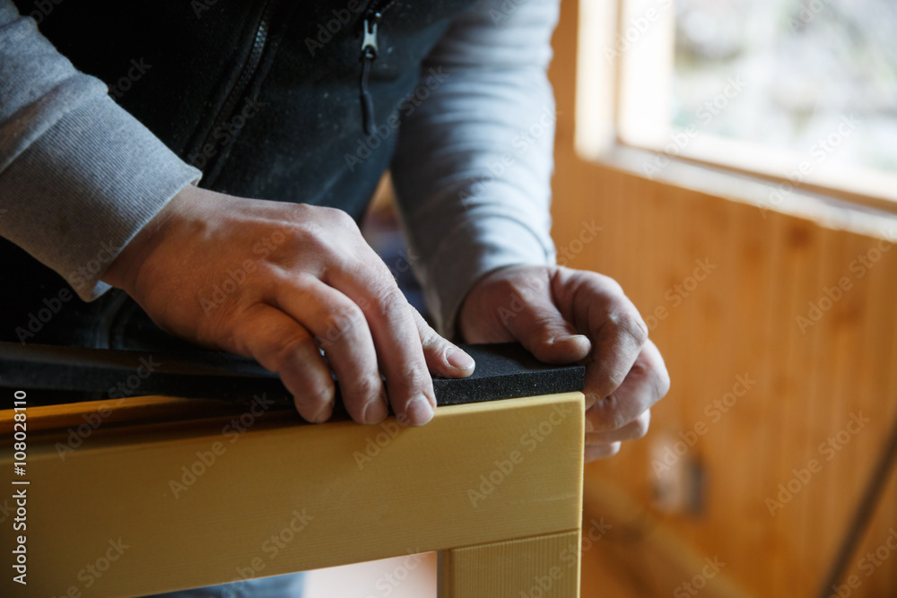 Worker preparing to install new three pane wooden windows in an old wooden house. Home renovation, sustainable living, energy efficiency concept. .