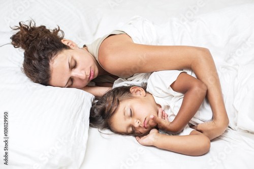 Sleeping kid girl and her mother in the bed.