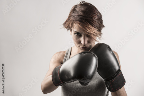 donna boxer sta per sferrare un pugno con i suoi guantoni neri © alex.pin