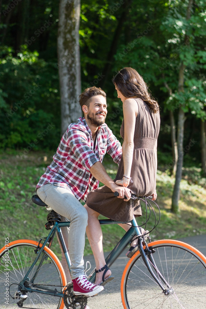 beautiful couple riding a city bike and smiling to each other