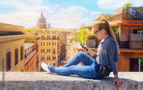 Photography Young woman sitting on wall and holding a smartphone, communication concept, Rom