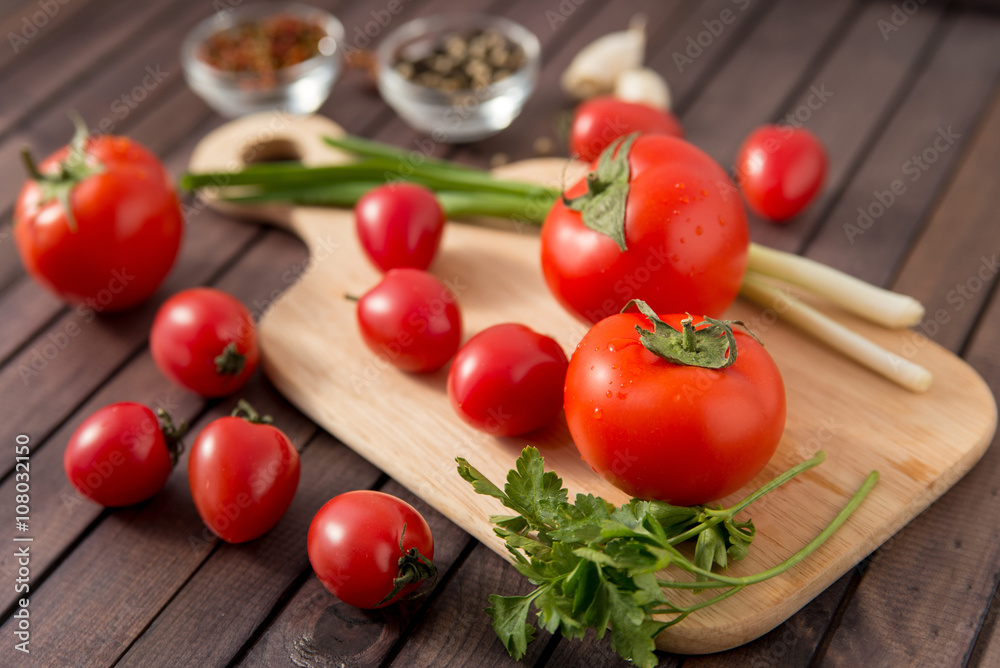 close up of fresh red delicious tomatoes with greenery on an old wooden background close up of fresh red delicious tomatoes with greenery on an old wooden background