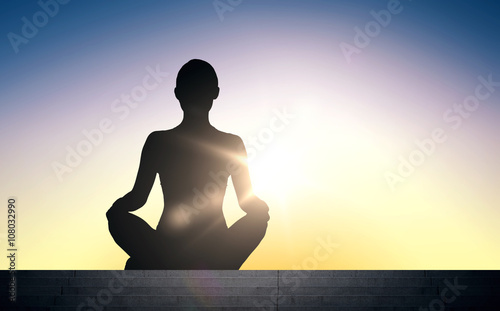 woman meditating in yoga lotus pose over sun light