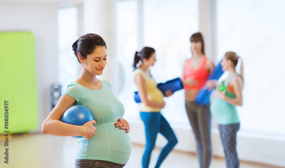 happy pregnant woman with ball in gym