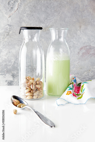 fresh homemade pistachio milk in a transparent bottle and pistac photo