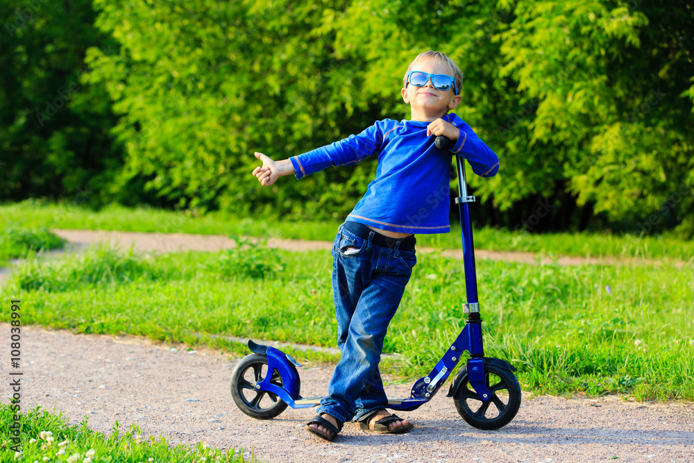 Fototapeta premium happy little boy enjoy riding scooter in summer