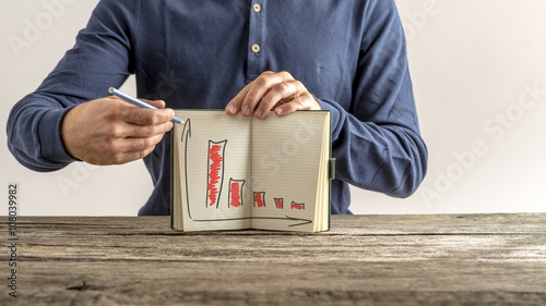 Businessman showing his notebook with falling financial graphs photo