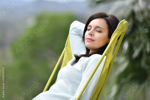 Dark-haired woman relaxing in long chair photo