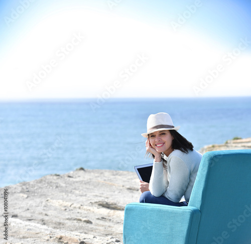 Woman using laptop by the sea, sit in armchair