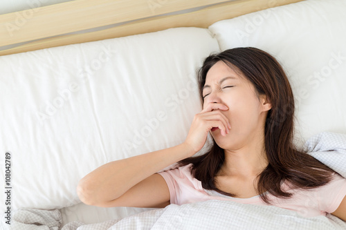 Woman yawning and lying on bed