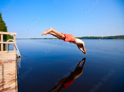 Fotografie Young man jumping into water