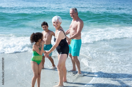 Happy grandparents with children standing at beach  © WavebreakMediaMicro