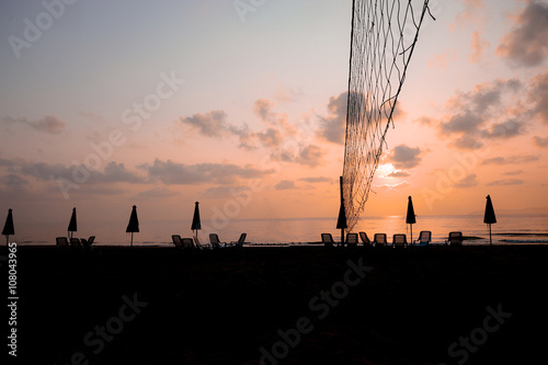 sunset and volleyball net at the beach with chairs