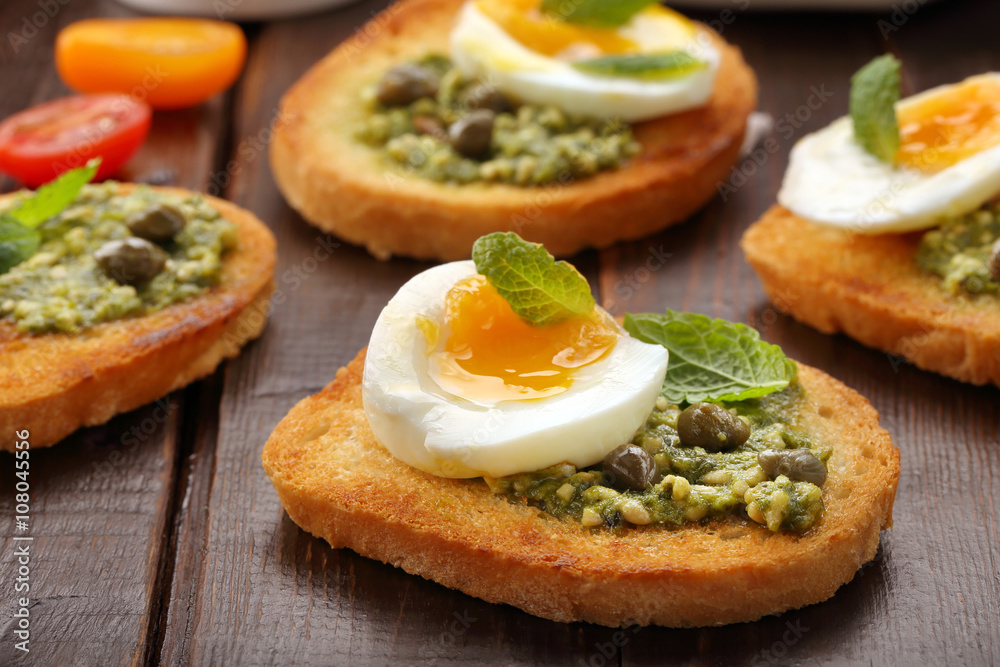 Fresh toasts with pesto and egg on wooden background Fresh toasts with pesto and egg on wooden background