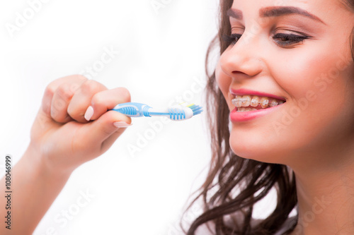 Portrait of a beautiful woman with braces on the teeth  cleans teeth with toothbrush  isolated on a white background