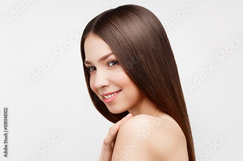 Young beautiful brunette woman with natural makeup on grey backg