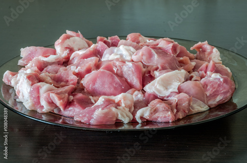 Glass plate on black table with fresh chopped pork meat for meal preparation photo