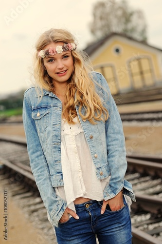 Junge Frau in Hippie-Kleidung posiert an einem Bahnhof